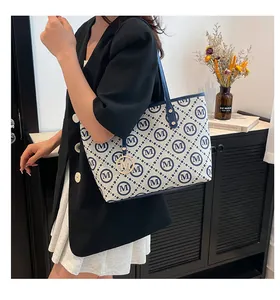 Détail du sac cabas beige avec motif M bleu et breloque logo en métal doré