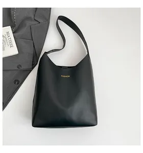 Vue à plat d'un sac cabas noir vintage avec inscription dorée à côté d'un blazer chic