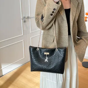 Chic black woven bucket bag with gold chain strap and deer charm on female model