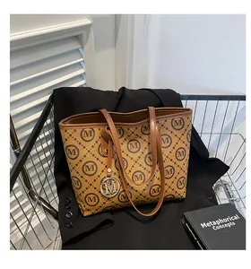 Détail du sac cabas à carreaux avec pendentif M en métal dans un chariot