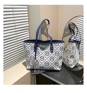 Détail d'un sac cabas à damier bleu et blanc avec motifs M et pendentif en métal