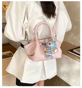 Pink pebbled leather bucket bag with top handle and knitted bear charm detail