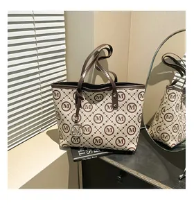 Détail d'un grand sac cabas à carreaux avec pendentif M argenté sur table noire