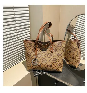 Gros plan d'un sac cabas marron à monogramme avec breloque logo M doré sur un meuble