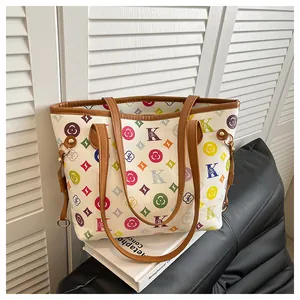 Detailed view of colorful monogram print on a large white tote bag with brown straps