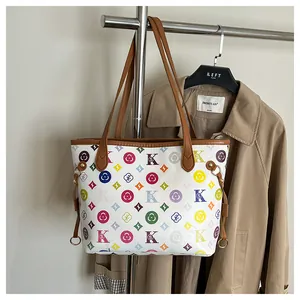 Detailed view of the white tote bag featuring colorful monogram patterns and brown leather strap