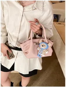 Detail of pink lychee leather handbag with a cute bear charm and round handles