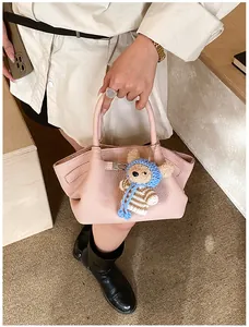 Detailed macro view of pink litchi leather bucket bag with cute crochet bear charm