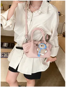 Detail of pink lychee grain leather bucket bag with a cute blue teddy bear pendant