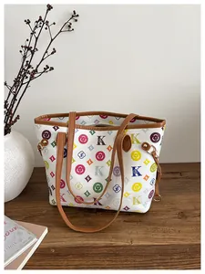 Detail of colorful monogram pattern and brown leather handles on a white tote bag
