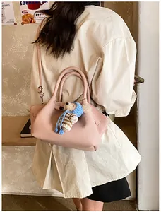Detail of pink lychee leather bucket bag featuring a cute bear charm and shoulder strap