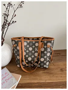Detailed view of vintage monogram tote bag with leather straps on a wooden surface