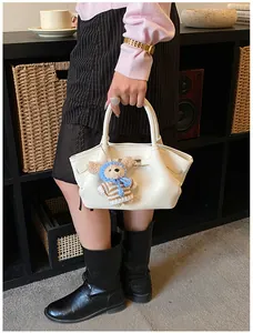 Close-up of off-white lychee grain bucket bag with silver twist lock and bear pendant