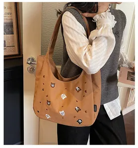 Detail of retro brown canvas hobo bag featuring colorful animal head embroidery and brand tag
