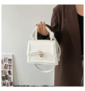 Close-up of a white leather crossbody bag with a gold metal lock and stitch details