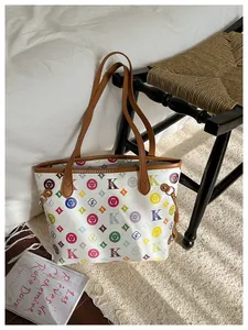 Detail view of large tote bag with colorful monogram print and brown leather handles