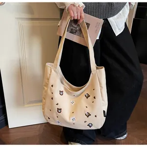 Close-up of off-white canvas tote with brown embroidered cat and bear cartoon patterns