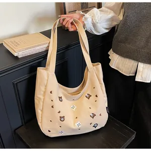Close-up of canvas tote bag featuring cute embroidered cartoon cats and bears with side label