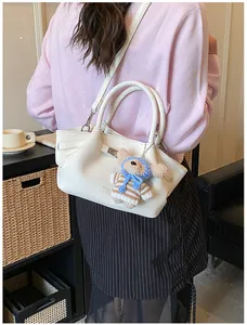 Close-up of a white lychee-patterned bucket bag with a cute brown teddy bear keychain