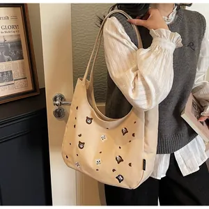 Close-up of beige canvas tote bag with colorful animal embroidery on shoulder