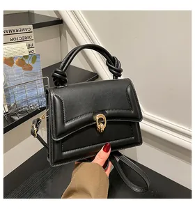 Detail of black leather handbag with knotted handle and elegant gold oval buckle