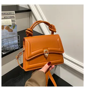 Detail of caramel crossbody bag with knotted handle and elegant gold metal lock