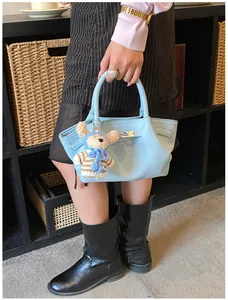 Light blue lychee leather bucket bag styled with a cute blue teddy bear plush charm