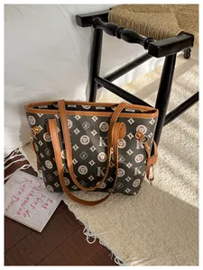 Detailed macro view of monogram tote bag featuring brown leather straps and metal hardware