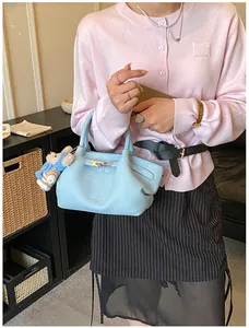 Detail of light blue lychee pattern bucket bag with metal buckle and plush bear charm