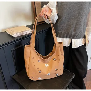 Close-up of brown canvas tote bag featuring detailed cat embroidery and brand label