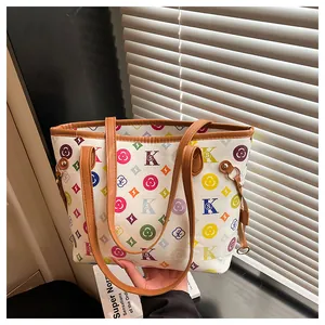 Detail of colorful letter patterns and brown leather straps on a large tote bag