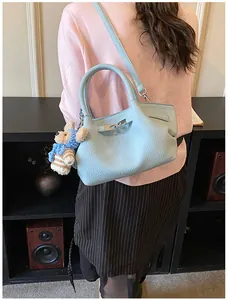 Detail of light blue bucket bag featuring a textured finish and cute bear charm pendant