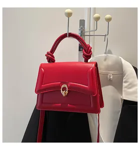 Detail of red square handbag with a knotted handle and golden double-ring buckle