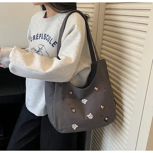 Detail of grey canvas hobo bag featuring colorful cat and bear embroidery for women