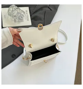 Detailed interior of a white shoulder bag with black lining and golden metal clasp