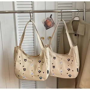 Detail view of beige canvas tote bags with cute animal embroidery and round crescent shape