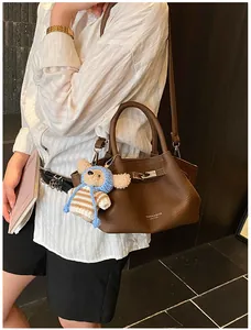 Detail of dark brown leather bucket bag with cute bear charm and silver hardware clasp