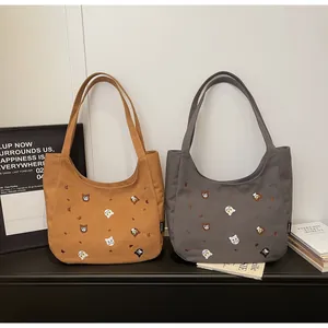Detail view of embroidered cat motifs on durable canvas tote bags in brown and gray
