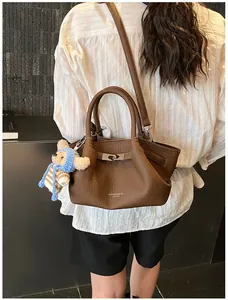 Detail of dark brown lychee leather bucket bag with silver buckle and bear charm