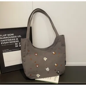 Detail of embroidered cartoon cats on a grey canvas moon-shaped tote bag