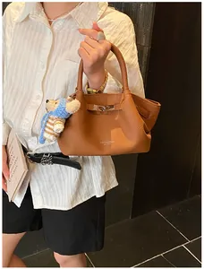Detail of brown litchi pattern leather bucket bag with silver lock and plush bear charm