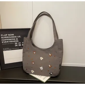 Detailed embroidery of tiger motifs and branded label on grey canvas tote bag