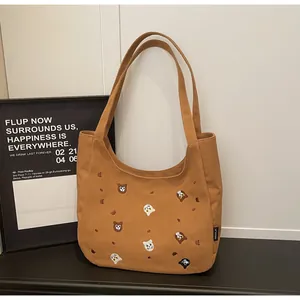 Close-up of brown canvas tote bag featuring detailed animal head embroidery and woven label