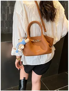 Close-up of caramel leather bucket bag with a bear charm and silver buckle detail