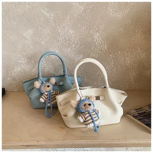 Detail of light blue and beige bucket bags with lychee grain leather and cute bear charms