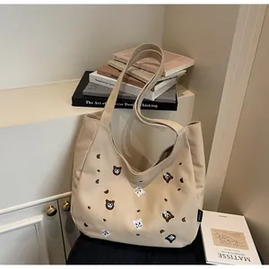 Close-up of beige canvas tote bag with detailed cat and bear embroidery patterns