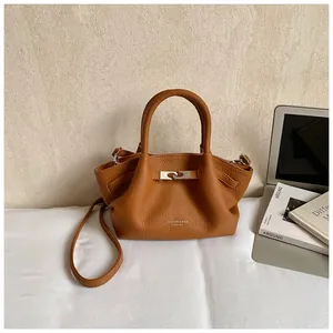 Close-up of caramel leather bucket bag detailing side folds and metallic buckle