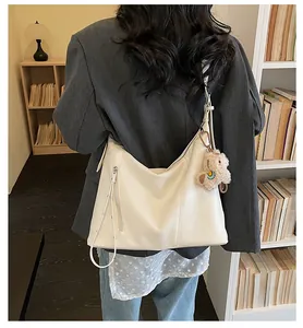 Sac à bandoulière beige minimaliste avec fermeture éclair latérale et pendentif ours en peluche