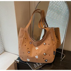 Close-up of brown canvas tote bag with detailed cat and bear embroidery patterns