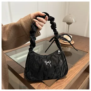 Détail du sac à bandoulière en velours noir plissé avec nœud argenté et anse froissée